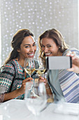 Women with white wine taking selfie in restaurant