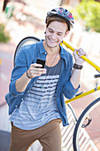Young man carrying bicycle and texting