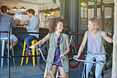 Women on bicycles outside cafe patio