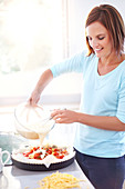 Woman preparing tomato quiche in kitchen