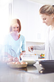 Women baking in sunny kitchen