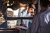 Mechanic and customer talking under car