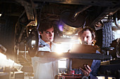 Mechanics with clipboard under car