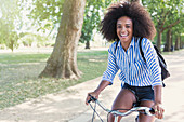Woman with afro riding bicycle in park