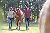 Couple walking horse in rural pasture