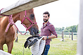 Man removing saddle from horse