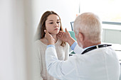Doctor checking teenage patient's glands