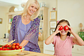 Playful girl covering eyes with tomatoes