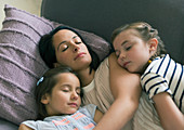 Mother and daughters napping on sofa