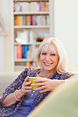 Senior woman drinking coffee on sofa