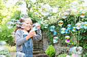 Girl blowing bubbles in backyard