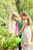 Girls watering plants in garden