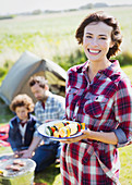 Woman with vegetable skewers at campsite
