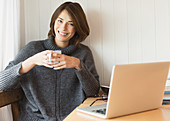 Woman drinking coffee at laptop