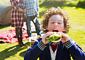 Boy taking large bite of hamburger