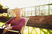 Senior woman sitting outside greenhouse