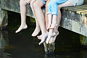 Family dangling bare feet over dock