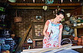 Woman hammering wood boards in workshop