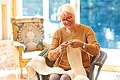 Senior woman knitting in living room