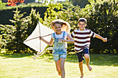 Brother and sister running with kite