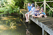 Family relaxing on footbridge over pond