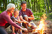 Family roasting marshmallows at campfire