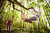 Father pushing daughter on rope swing