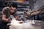 Craftsman chiselling wood in workshop