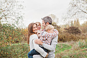 Smiling family hugging in autumn park