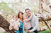 Portrait smiling family in front of tree