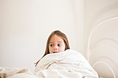 Toddler girl sitting up in bed