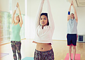 Woman with arms overhead in yoga class