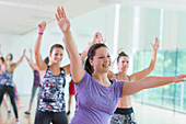 Woman with arms raised in exercise class