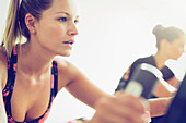 Focused woman riding exercise bike