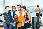 Friends using cell phone on exercise bike