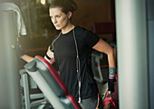 Focused woman stretching leg at gym