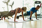 Man and woman doing planks at gym