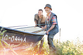 Father and adult son lifting fishing boat
