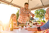 Man serving salad at sunny patio table