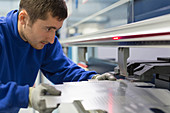Worker operating laser cutter in factory