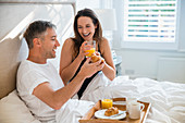 Smiling couple enjoying breakfast in bed