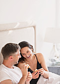 Laughing couple eating in bed