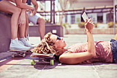 Woman with tablet laying on skateboard