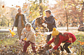 Family playing in autumn leaves at park