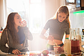 Girls making smoothie in sunny kitchen
