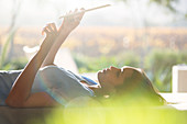 Woman laying and using tablet on patio
