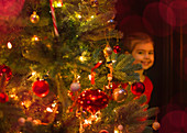 Girl hiding behind Christmas tree