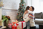 Mother and daughter hugging near gifts