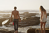 Young couple walking on rocks at ocean