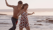 Playful young couple running on beach